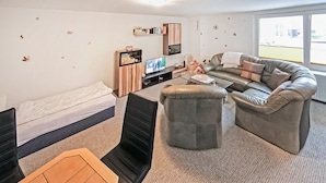 A compact living space with a bed, a sofa, a small table, and a TV. - Ferienhaus Trassenheide (Trassenheide (Ostseeba)