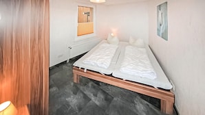 A room with a bed, a radiator, a window, and a lamp. - Ferienhaus Trassenheide (Trassenheide (Ostseeba)