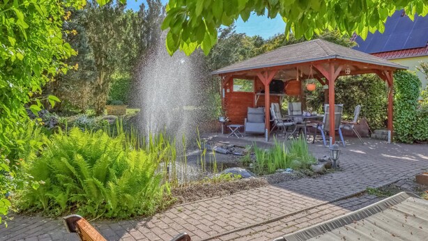 A garden with a fountain, a gazebo, and outdoor seating. - Wohnung Nordwestuckermark (Nordwestuckermark)