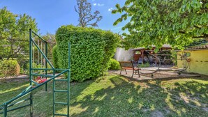 A garden with a climbing frame, a bench, and a patio area with outdoor furniture. - Wohnung Nordwestuckermark (Nordwestuckermark)