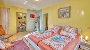 A double bed with floral bedding, a wooden chair, a small table, and a fireplace. - Wohnung Nordwestuckermark (Nordwestuckermark)