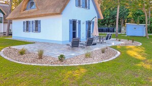 Una casa con techo de paja y un patio con mobiliario exterior.