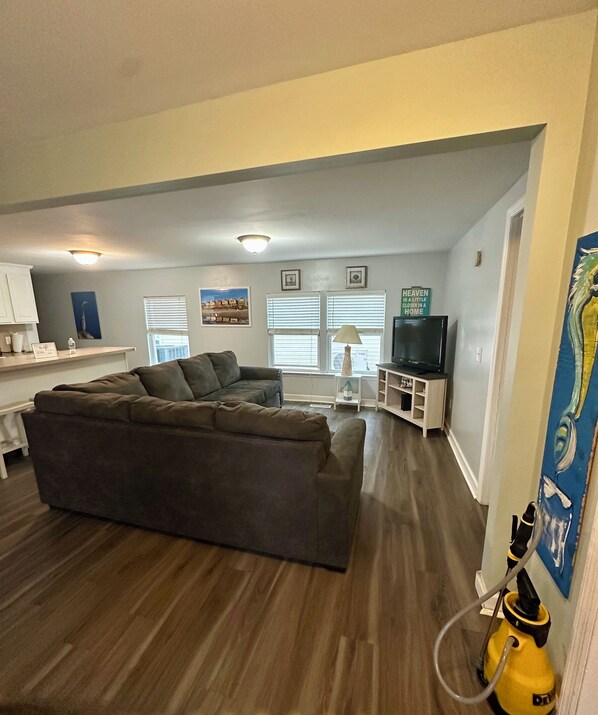 Una sala de estar moderna con un sofá modular, un televisor de pantalla plana y un comedor con una mesa y sillas blancas.