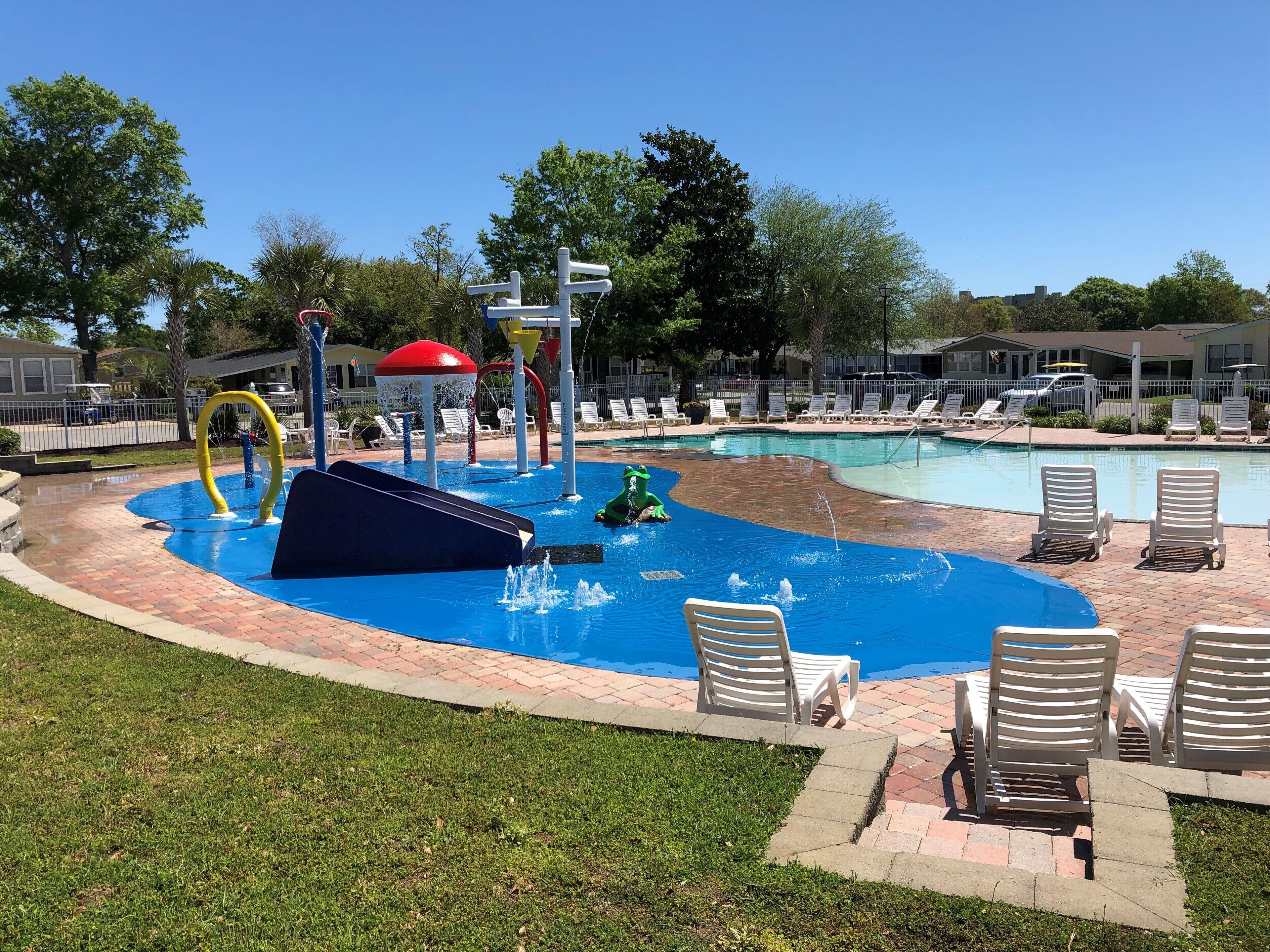 A pool area with a water slide, lounge chairs, and a small kiddie pool.
