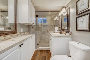Un bagno moderno con doccia a filo pavimento, un water e un lavandino.