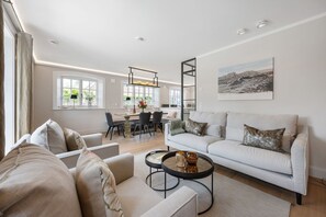Un vaste espace de vie comprenant un ensemble de canapés, une table basse et un coin repas avec des chaises et une table.
