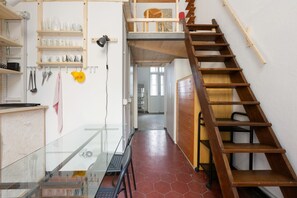 A kitchen with wooden shelves, a staircase, and a glass railing. - GuestHost - Milan Cadore - Urban Retreat Apartment! (Milano)