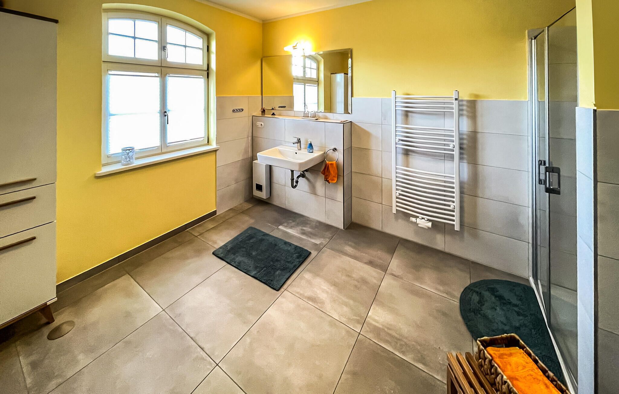 Ein Badezimmer mit Waschbecken, Spiegel, Handtuchhalter und einer Duschkabine.