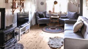 Ett mysigt vardagsrum med en öppen spis, en tv och bekväma sittplatser.