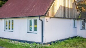 En vit byggnad med ett rött tak och en liten veranda.