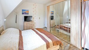 Een slaapkamer met een bed, een televisie, een kledingkast en een spiegel.