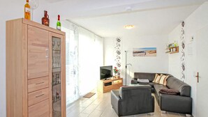 Een moderne woonkamer met een houten kast, een grijze bank, een televisie en een vloerlamp.