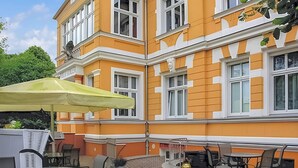 A building with a yellow facade, multiple windows, and outdoor seating with tables and chairs. - Nice apartment in Ahlbeck (Seebad) with kitchen (Ahlbeck (Seebad))