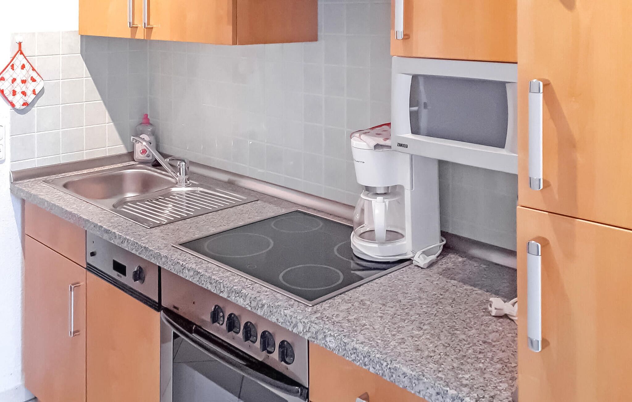 A kitchen with a stove, microwave, sink, and a coffee maker.