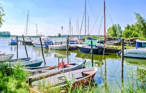 En småbåtshamn med olika typer av båtar förtöjda, omgiven av grönska och träd.