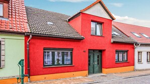 Un edificio rojo con puerta y ventanas verdes, junto a un edificio verde con tejado de tejas.