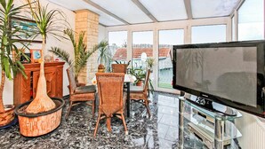 Amplia sala de estar con un televisor grande, asientos cómodos y vistas a la ciudad.
