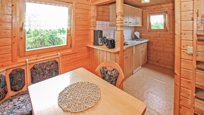 A wooden cabin with a dining area, kitchen, and a window with a view of greenery. - Stunning home in Kummerow with sauna (Kummerow)