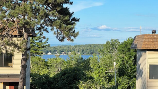 A residential area with a view of a lake and forested hills. - Lake Winnipesaukee, Weirs Beach! (Laconia)