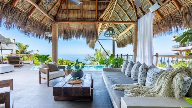 A spacious outdoor lounge with a thatched roof, comfortable seating, and a view of the ocean. - Las Villas Puerto Vallarta (Puerto Vallarta)