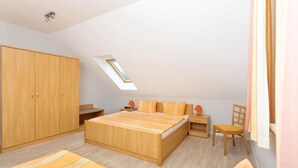 Une chambre avec un puits de lumière, des meubles en bois et un lit avec une literie à rayures.
