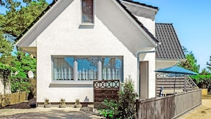 Une maison de plain-pied avec un toit à pignon, une grande fenêtre avec des rideaux et une petite porte.