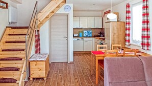 Un espace de vie compact comprenant un escalier en bois, un coin repas et une cuisine.