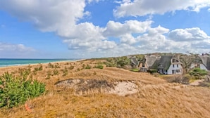 Un paysage côtier avec des maisons, une plage et un ciel dégagé.