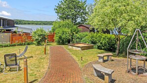 A garden area with a brick pathway, benches, a swing set, and a small pond.