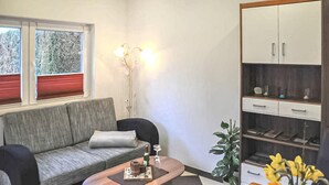 Ein Wohnzimmer mit Sofa, Couchtisch, Schrank und einer Topfpflanze.