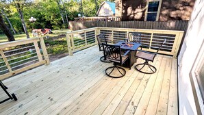 A wooden deck with a metal table and chairs, surrounded by a wooden fence and a wooden deck railing. - Lake Fork Luxury and Leisure. 2 story cabin in gated resort. Many amenities! (Quitman)
