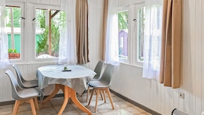 Un coin repas avec une table ronde, quatre chaises et de grandes fenêtres avec des rideaux.