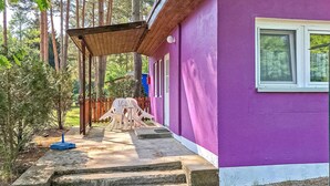 Un bâtiment violet doté d’un porche abrité, d’un escalier menant à l’entrée et d’une fenêtre.