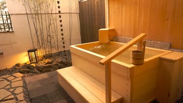 A wooden hot spring bath with a wooden bench and a small wooden structure on top.