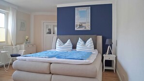 Een slaapkamer met een bed, een stoel, een bureau en een nachtkastje.