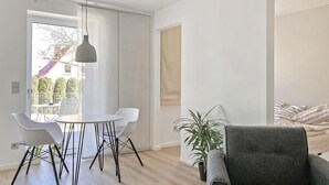 A modern living room with a round table, two white chairs, a grey armchair, a hanging light fixture, and a potted plant. - 1 bedroom pet friendly apartment in Poseritz (Poseritz)