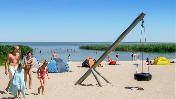 En strand med tält, en gunga och en del folk.