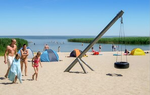 A beach with tents, a swing set, and people. - Ferienhaus Ueckermünde Bellin (Ueckermünde OT Bellin)
