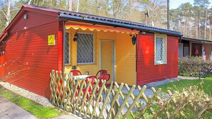 En röd och gul byggnad med en inhägnad veranda, en dörr och ett fönster.