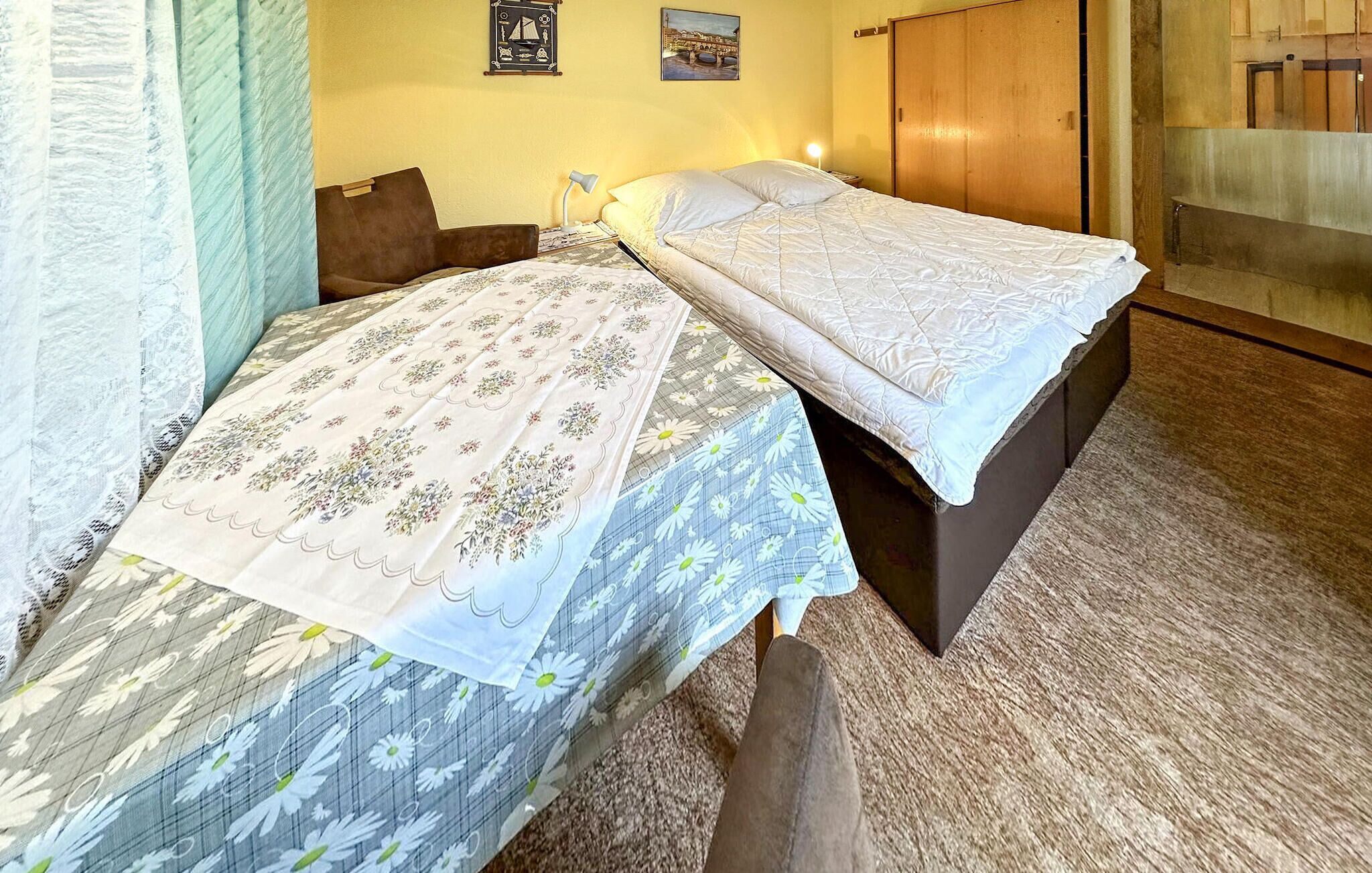 A double bed with floral bedding, a bedside table, and a nightstand.