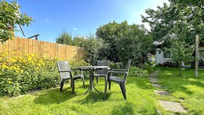 A patio with a table and chairs, surrounded by a wooden fence and lush greenery. - Ferienwohnung Zinnowitz Seebad (Zinnowitz (Seebad))