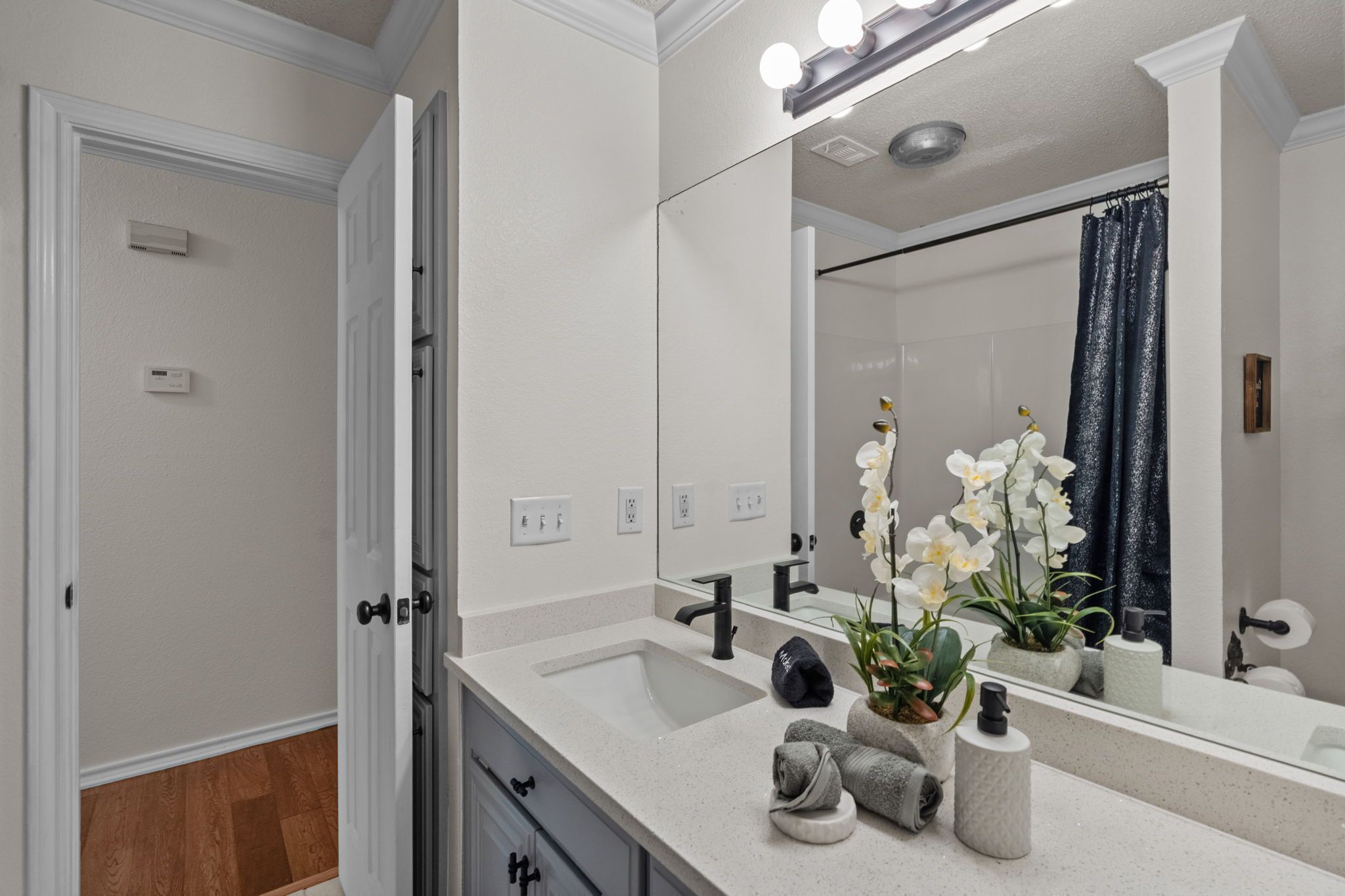 A modern bathroom with a large mirror, a sink, and a shower.