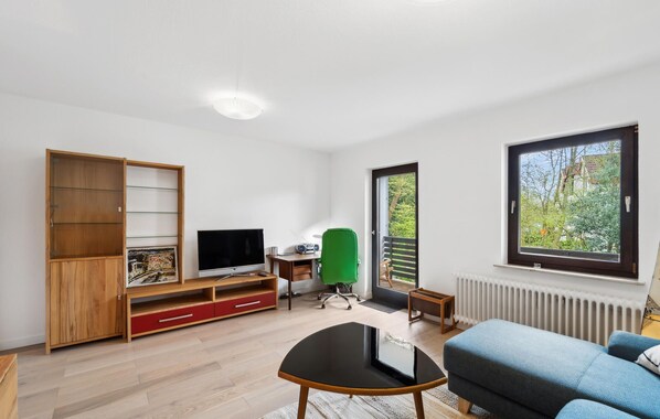 A modern living room with a TV, green office chair, and a blue sofa.