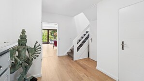 A modern interior with a staircase, a door, and a view of a balcony with greenery.
