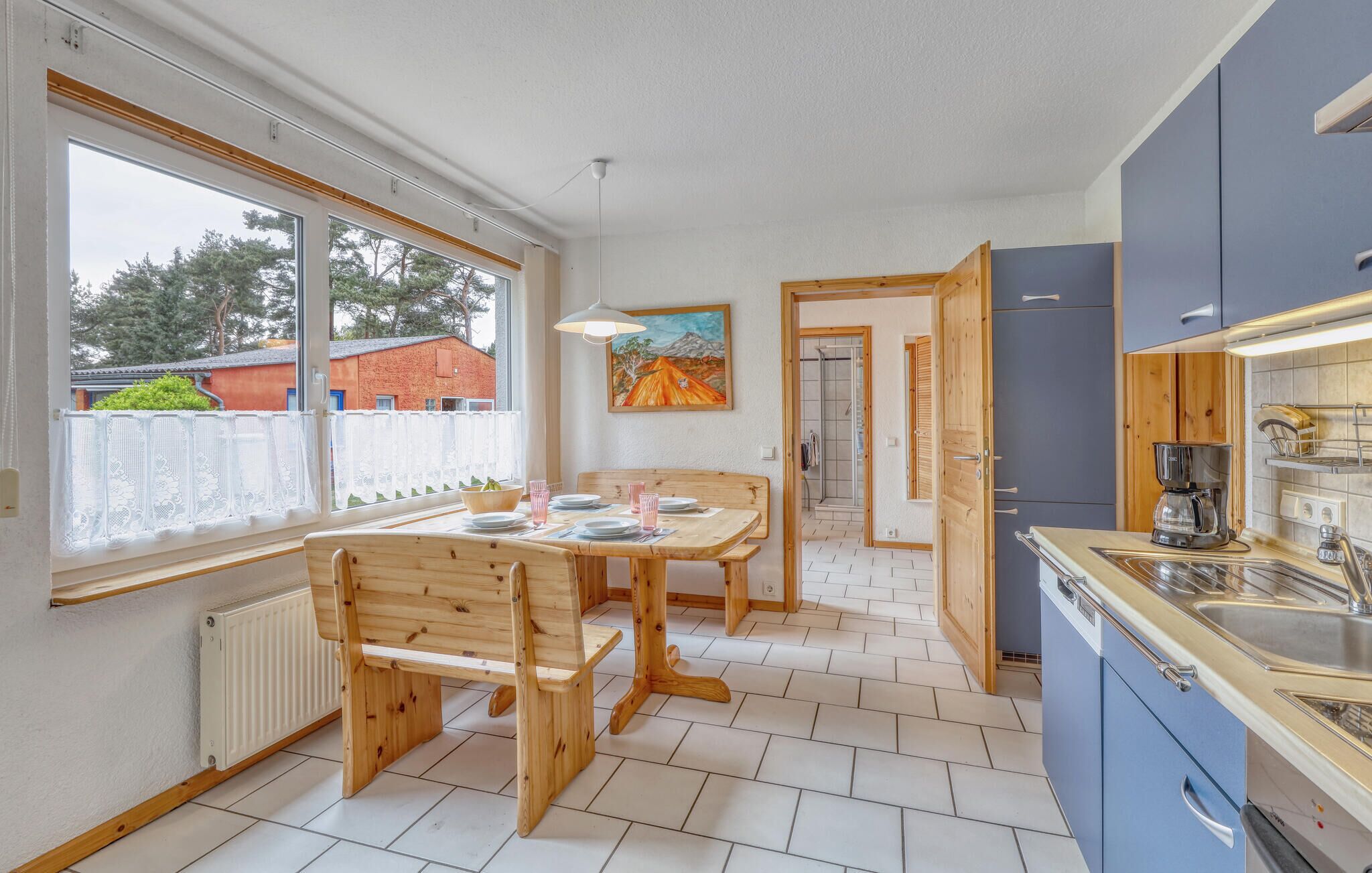 A modern kitchen with a dining area, wooden furniture, and a view of the outside.