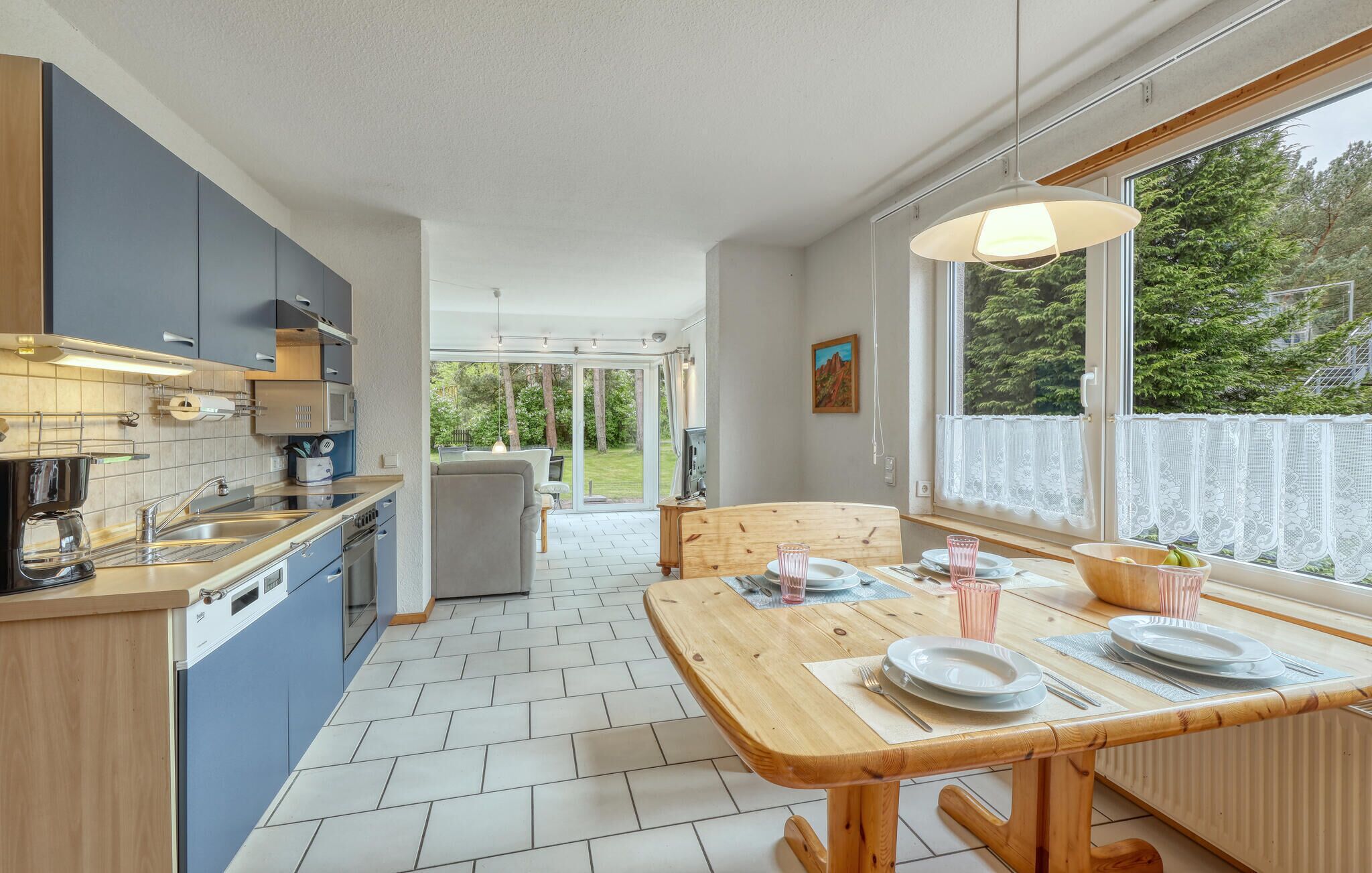 A modern kitchen with a dining area, large windows, and a view of the outdoors.