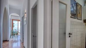 A hallway with a view to a balcony, a tiled wall, and a door leading to a room.