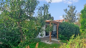 A house with a covered patio, surrounded by lush greenery and a clear sky. - Ferienwohnung Kölpinsee/Usedom (Kölpinsee/Usedom)