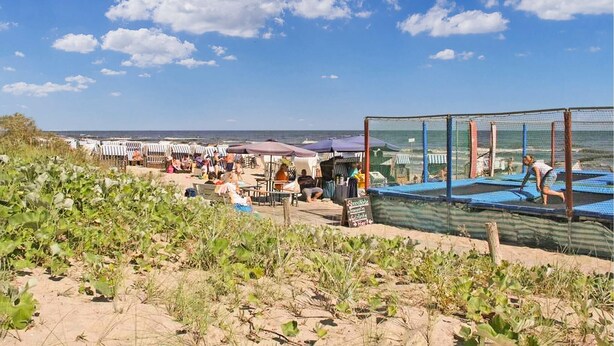 A beach with umbrellas, people, and a netted area. - Ferienwohnung Kölpinsee/Usedom (Kölpinsee/Usedom)