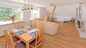 A modern living room with a wooden dining table, beige sofa, and a TV stand. - Ferienwohnung Zwiedorf (Zwiedorf)